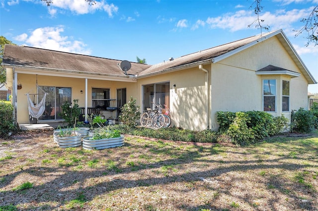 back of property featuring a garden and stucco siding