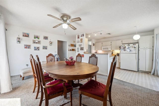 dining room with light carpet, ceiling fan, and a textured ceiling