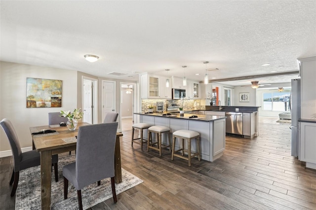 dining space featuring a textured ceiling, dark wood-style floors, baseboards, and ceiling fan