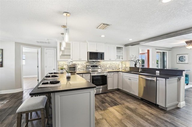 kitchen featuring a peninsula, visible vents, appliances with stainless steel finishes, and a sink