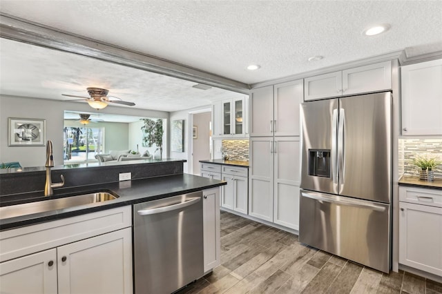 kitchen featuring dark countertops, light wood finished floors, stainless steel appliances, and a sink