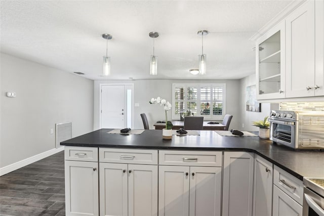 kitchen with visible vents, a peninsula, a toaster, white cabinetry, and dark countertops