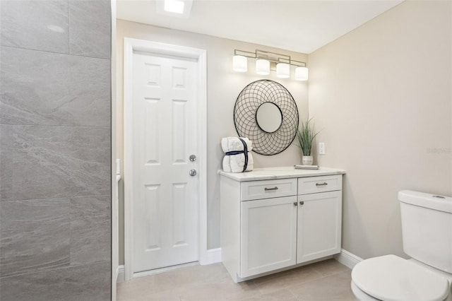 bathroom with toilet, vanity, and baseboards