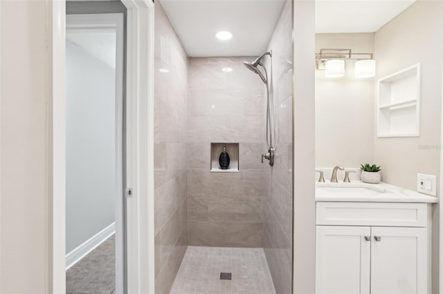 bathroom with tiled shower and vanity