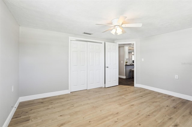 unfurnished bedroom with visible vents, a ceiling fan, a closet, light wood finished floors, and baseboards