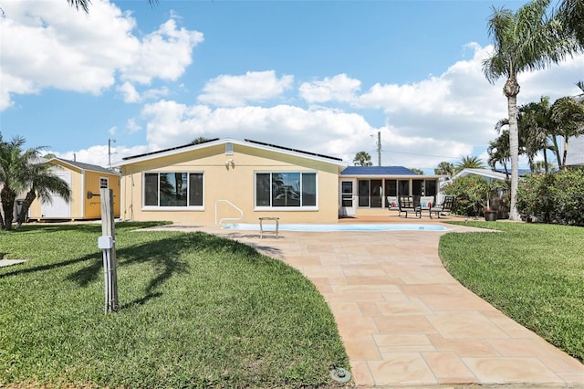 back of property with stucco siding, roof mounted solar panels, a patio, a yard, and a sunroom