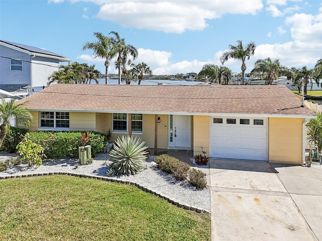 ranch-style house with a front yard, concrete driveway, an attached garage, and a shingled roof