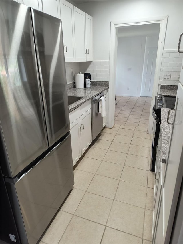 kitchen featuring white cabinets, stainless steel appliances, backsplash, and light tile patterned flooring