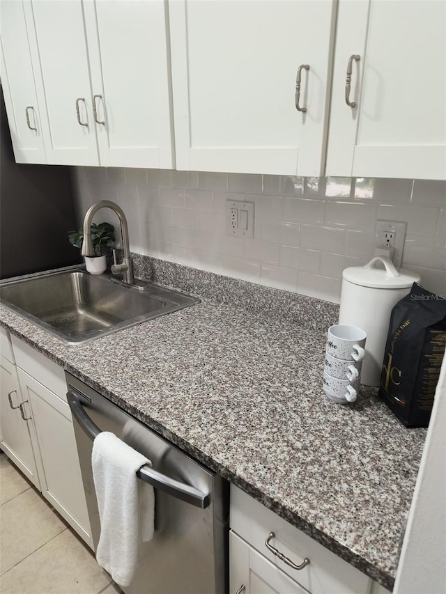 kitchen featuring stainless steel dishwasher, a sink, white cabinets, and tasteful backsplash