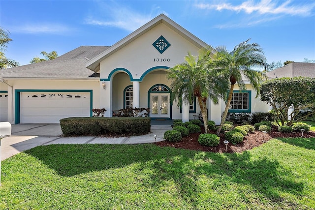 view of front of house featuring a garage, concrete driveway, french doors, stucco siding, and a front yard