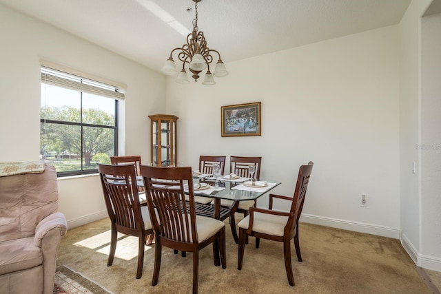 dining area featuring a notable chandelier, light colored carpet, and baseboards