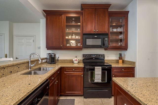 kitchen featuring light tile patterned floors, light stone counters, a sink, black appliances, and glass insert cabinets