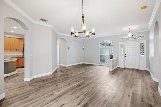 entrance foyer with visible vents, an inviting chandelier, ornamental molding, light wood-type flooring, and baseboards