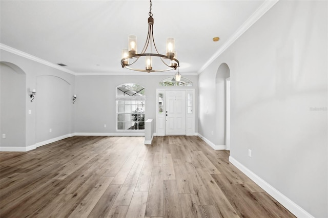 foyer entrance with visible vents, baseboards, arched walkways, wood finished floors, and crown molding