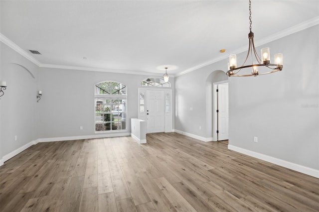 unfurnished living room featuring arched walkways, visible vents, ornamental molding, light wood-type flooring, and baseboards