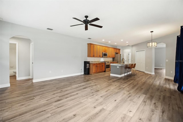 unfurnished living room with light wood-type flooring, arched walkways, baseboards, and recessed lighting