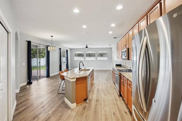 kitchen featuring stainless steel appliances, light wood-style floors, a sink, and brown cabinets