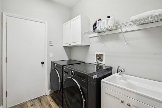 laundry room featuring a sink, cabinet space, light wood finished floors, and washer and dryer