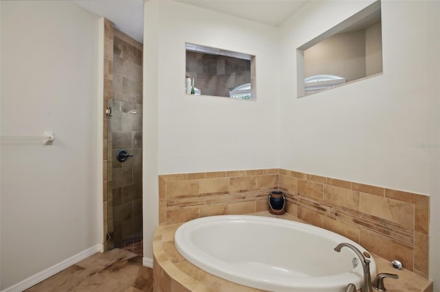 bathroom with a tile shower, a bath, and baseboards