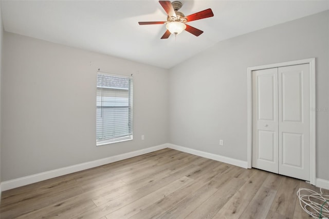 unfurnished bedroom featuring light wood-style floors, lofted ceiling, a closet, and baseboards