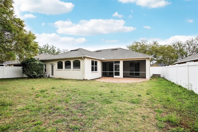 back of house featuring a sunroom, a fenced backyard, a yard, and stucco siding