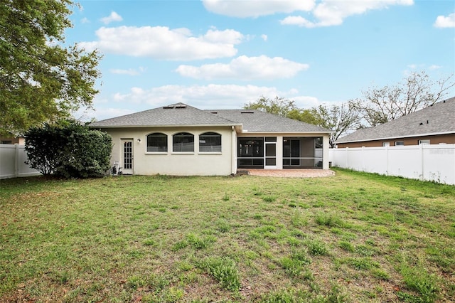 back of property with a yard, a shingled roof, a fenced backyard, and a sunroom