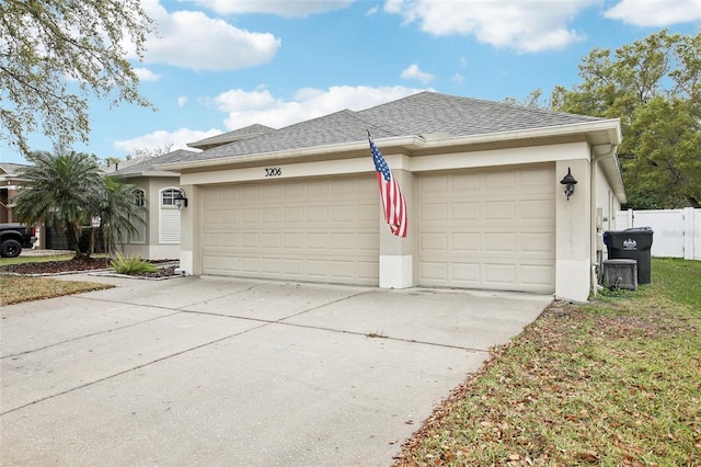 exterior space with concrete driveway, a shingled roof, an attached garage, and stucco siding