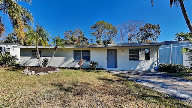 ranch-style house with driveway, a front lawn, and stucco siding