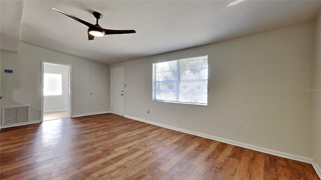 empty room with plenty of natural light, visible vents, ceiling fan, and wood finished floors