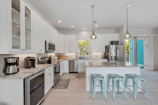 kitchen with white cabinetry, a breakfast bar area, stainless steel appliances, wine cooler, and backsplash
