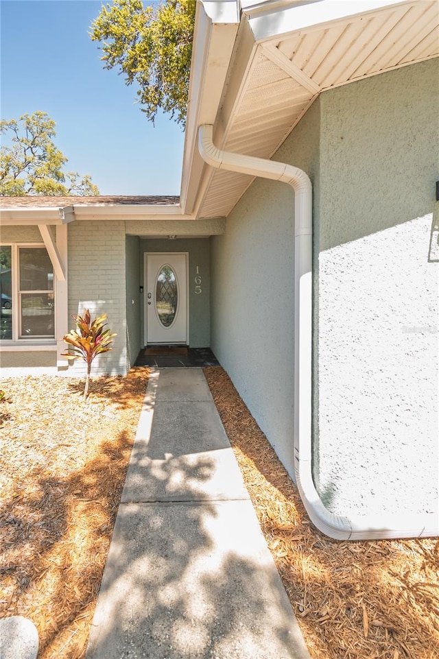 doorway to property featuring brick siding and stucco siding