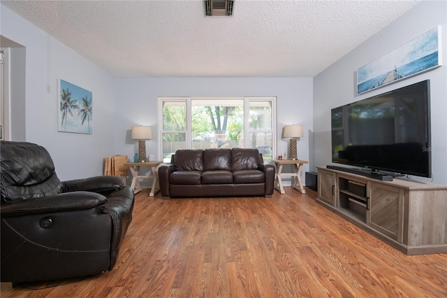 living room featuring wood finished floors, visible vents, and a textured ceiling