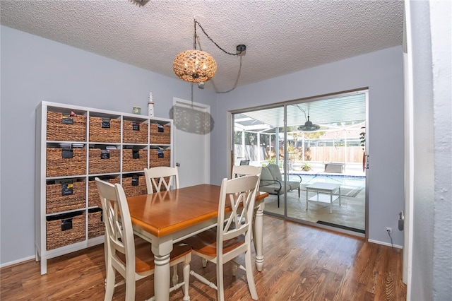 dining space featuring baseboards, a textured ceiling, wood finished floors, and a sunroom