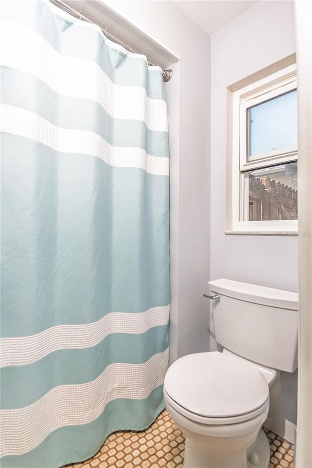 bathroom with toilet and a shower with curtain