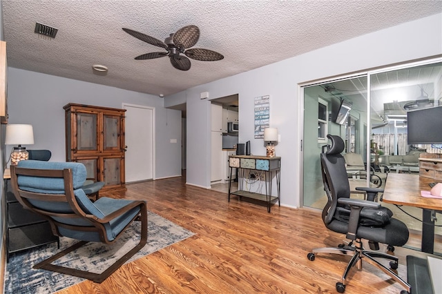 office area with visible vents, a textured ceiling, ceiling fan, and wood finished floors