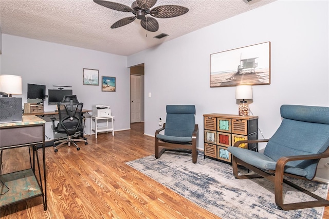 office featuring wood finished floors, baseboards, visible vents, ceiling fan, and a textured ceiling