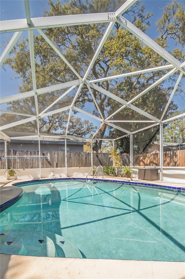 view of swimming pool featuring glass enclosure, a fenced in pool, and a fenced backyard