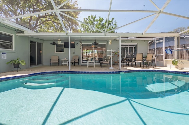 pool featuring a patio area, glass enclosure, and ceiling fan