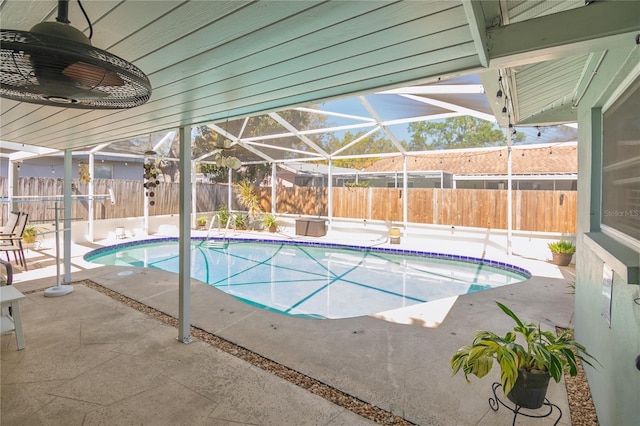 view of swimming pool featuring glass enclosure, a patio area, and a fenced backyard