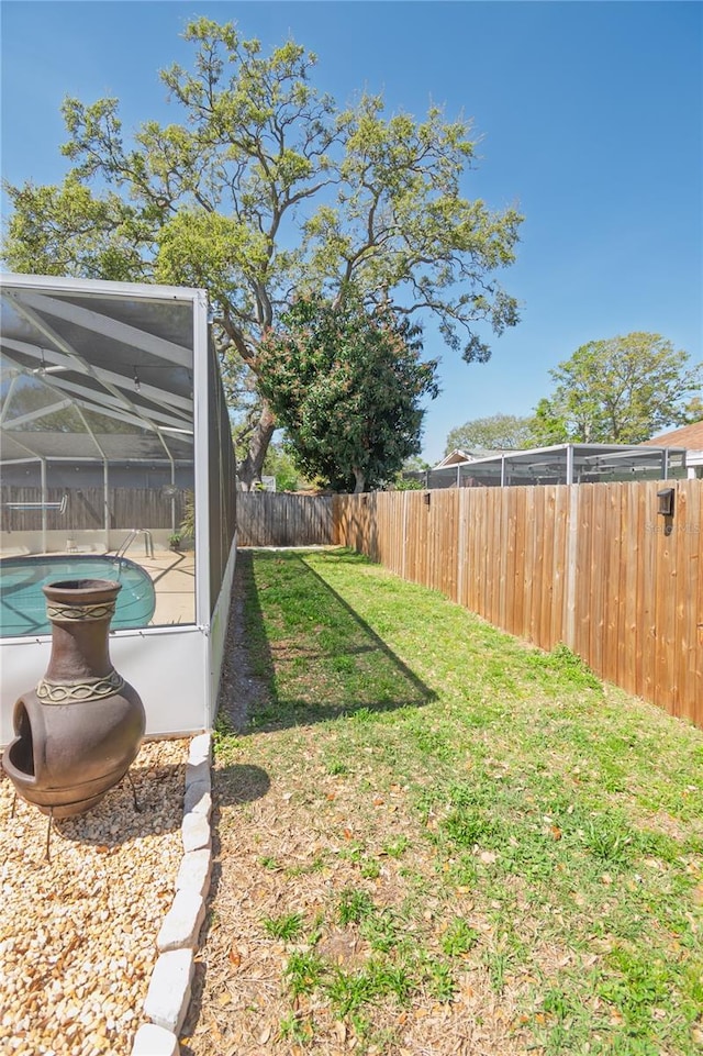 view of yard featuring glass enclosure, a fenced in pool, and a fenced backyard