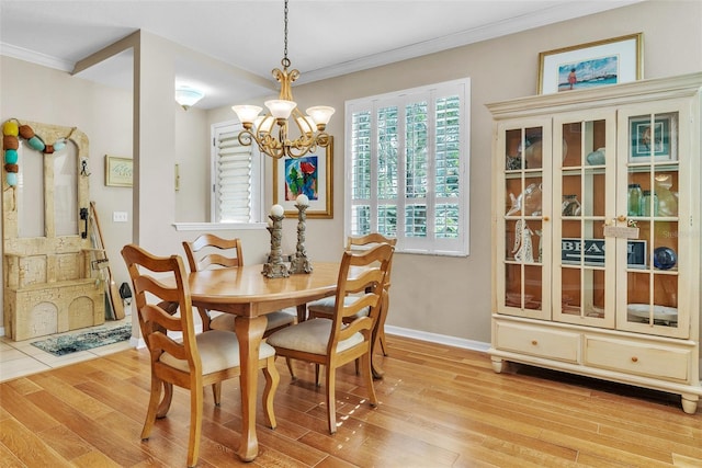 dining area with baseboards, light wood finished floors, a chandelier, and crown molding