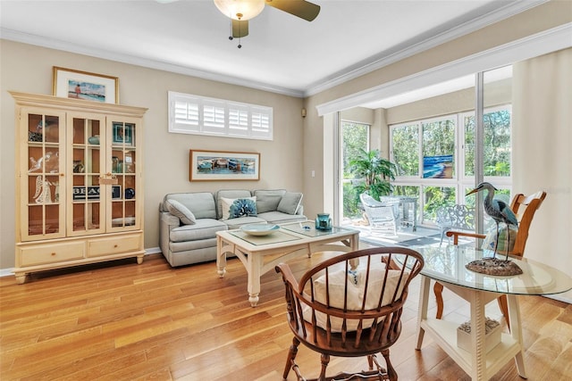 sitting room with ornamental molding, light wood-type flooring, a ceiling fan, and baseboards