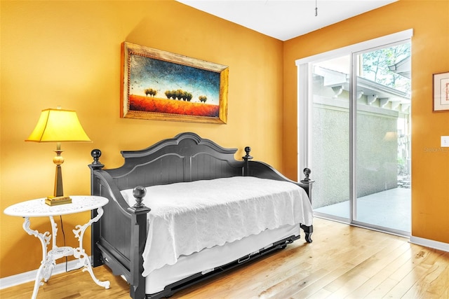 bedroom featuring access to exterior, baseboards, and wood finished floors