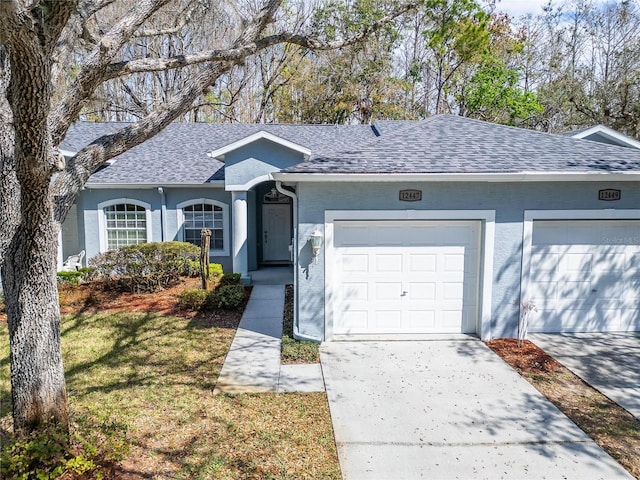 ranch-style house with a shingled roof, concrete driveway, a front yard, stucco siding, and a garage