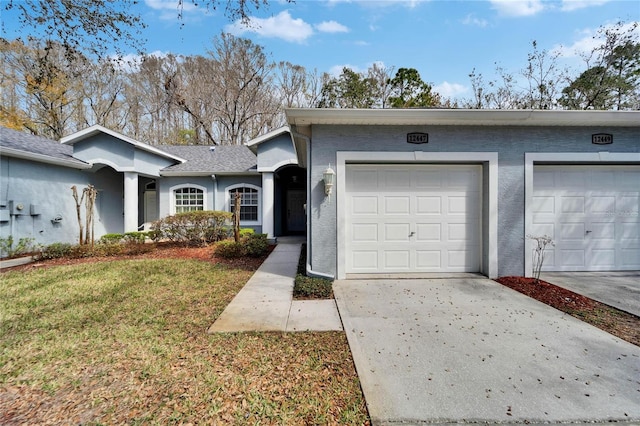 view of front of property with stucco siding, an attached garage, concrete driveway, and a front lawn