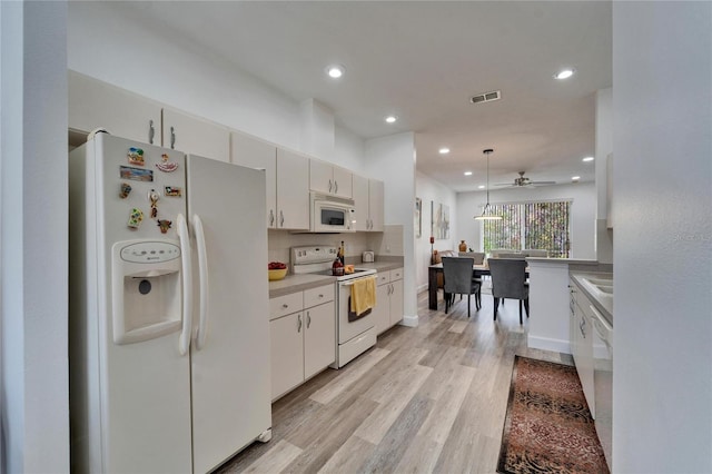 kitchen with white appliances, visible vents, light wood finished floors, light countertops, and decorative light fixtures