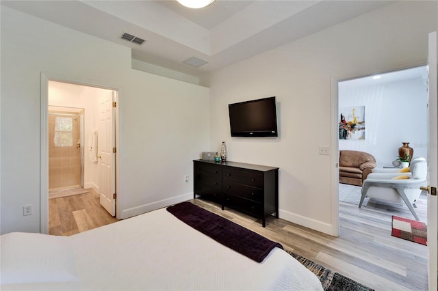 bedroom with visible vents, connected bathroom, baseboards, and wood finished floors