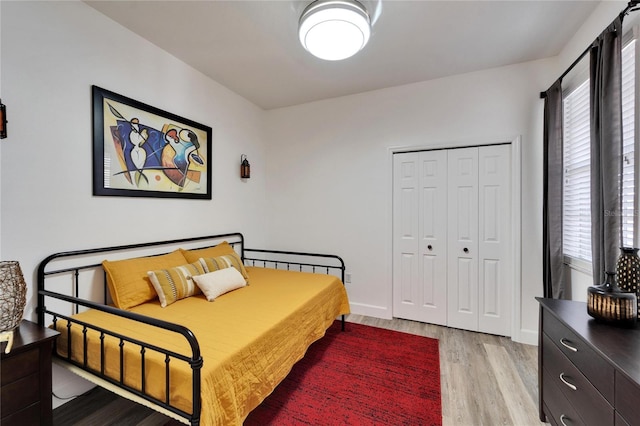 bedroom with light wood-style floors, a closet, and baseboards