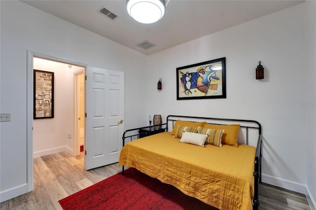 bedroom featuring baseboards, visible vents, and light wood finished floors