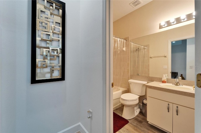 bathroom featuring visible vents, toilet, wood finished floors, shower / tub combo, and vanity